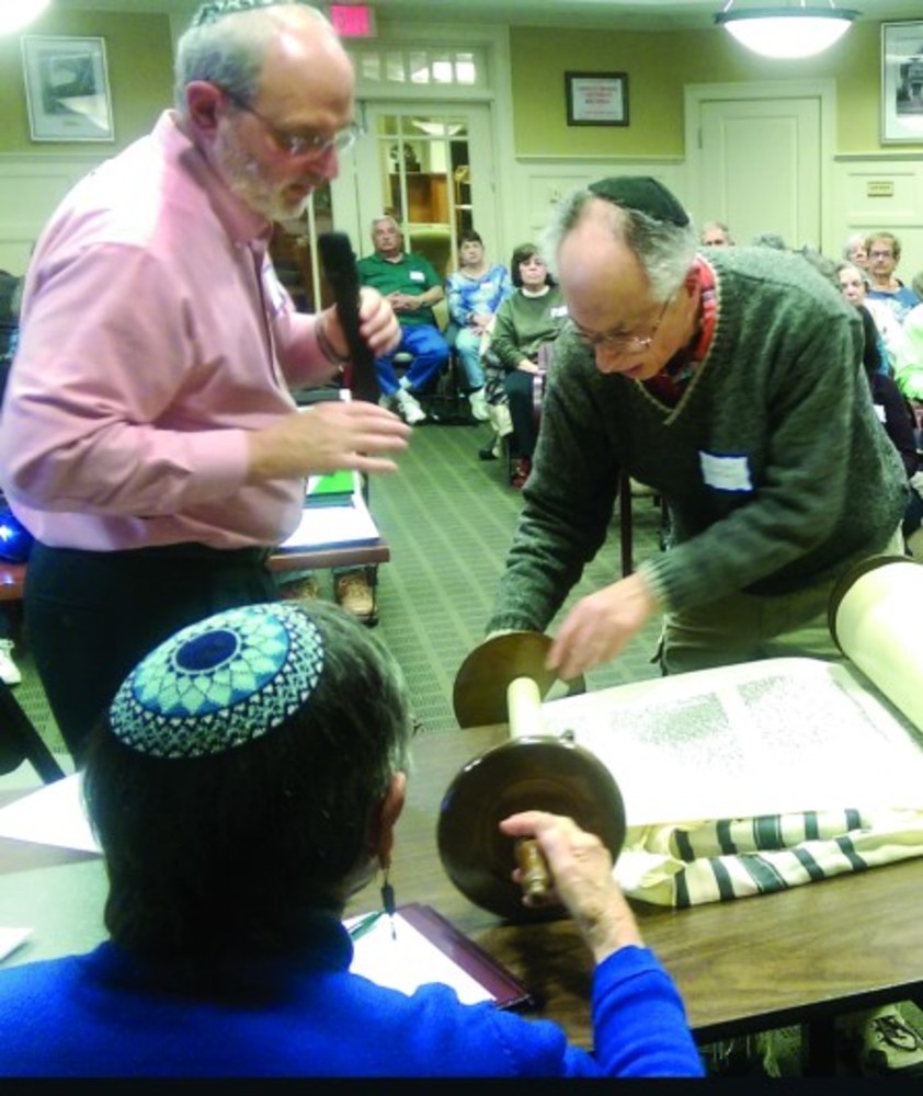 Michael Goldberg displays the Torah he has been repairing, while Rabbi Richard Perlman and Alice Goldstein look on. /PHOTO | NAOMI LIPSKY
